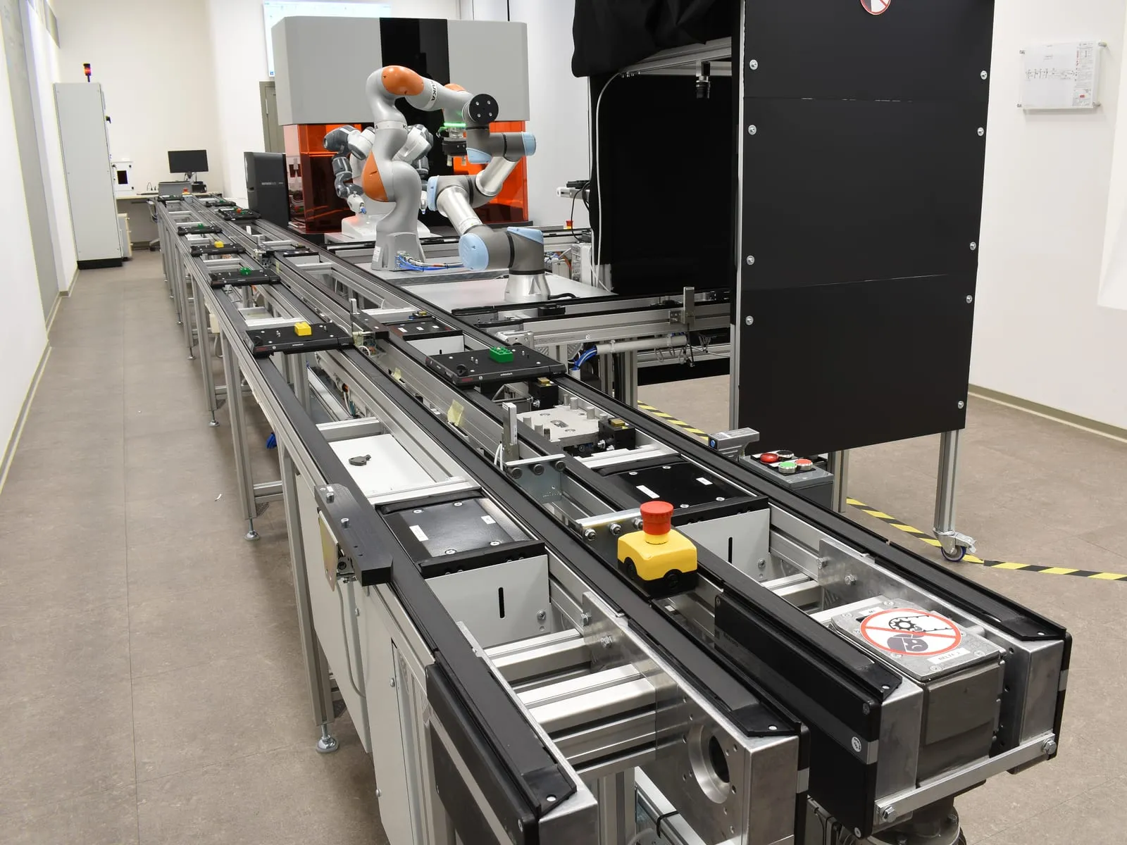 An assembly line of linked conveyor modules, with a collaborative robot arm working at the far end